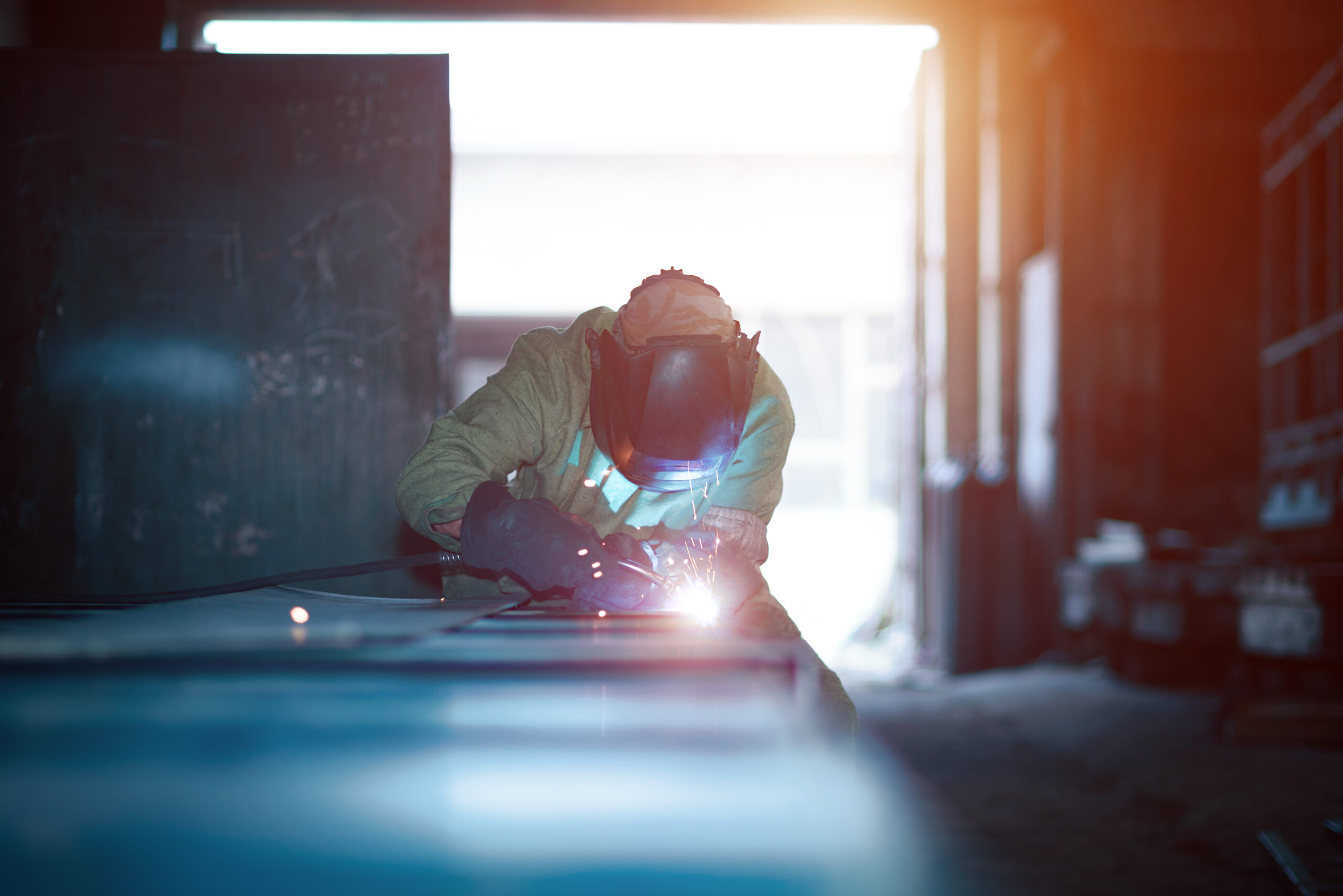 A welder with a welding machine works in a factory